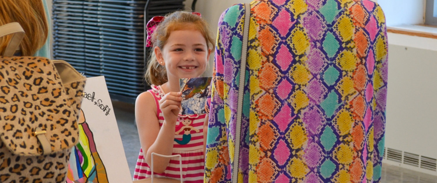 A Mud Daubers Summer Camper shows off their artwork to a family member