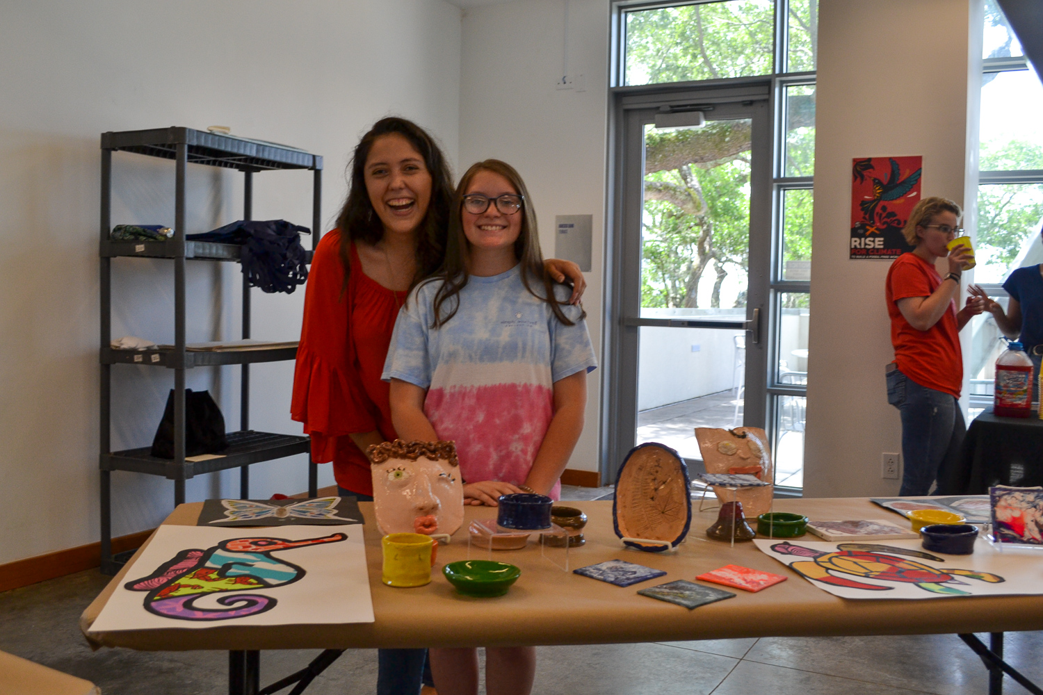 A Mud Daubers Summer Camper shows off their artwork with Education Director Pamela Cevallos